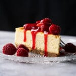Keto cheesecake slice with a graham cracker crust, berries and strawberry jelly