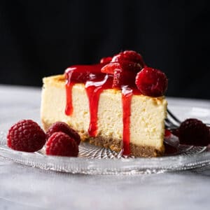 Keto cheesecake slice with a graham cracker crust, berries and strawberry jelly
