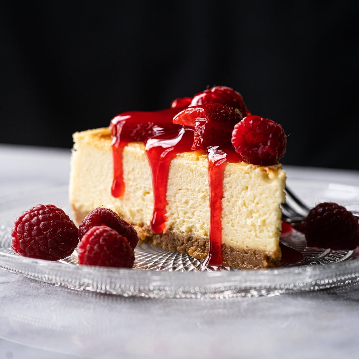Keto cheesecake slice with a graham cracker crust, berries and strawberry jelly