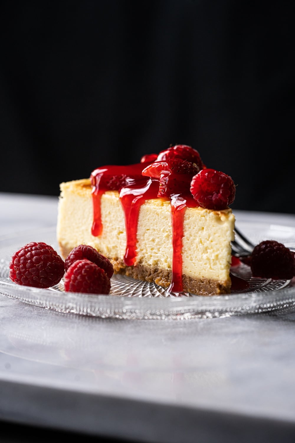 Keto cheesecake slice with a graham cracker crust, berries and strawberry jelly