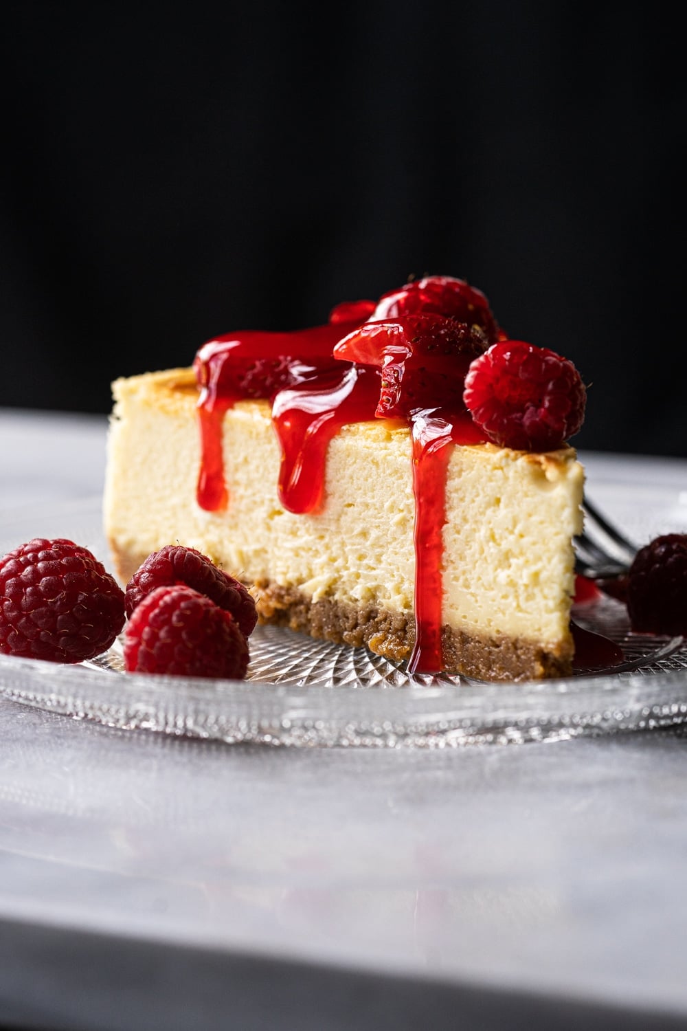Keto cheesecake slice with a graham cracker crust, berries and strawberry jelly