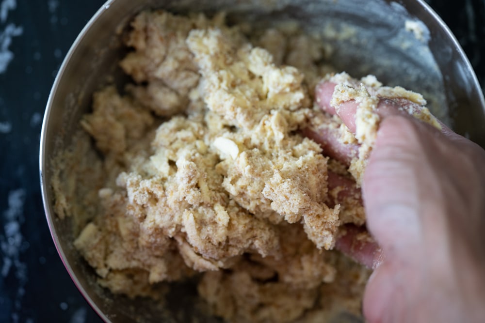 Mixing the keto shortcake dough with a hand in a gray bowl