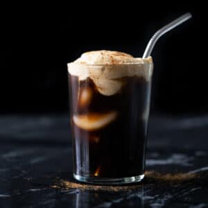 A keto pumpkin cream cold brew in a tall glass with a metal straw