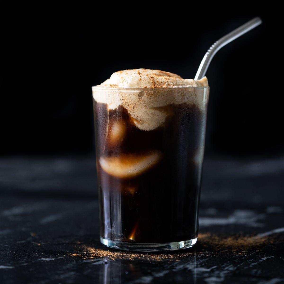 A keto pumpkin cream cold brew in a tall glass with a metal straw