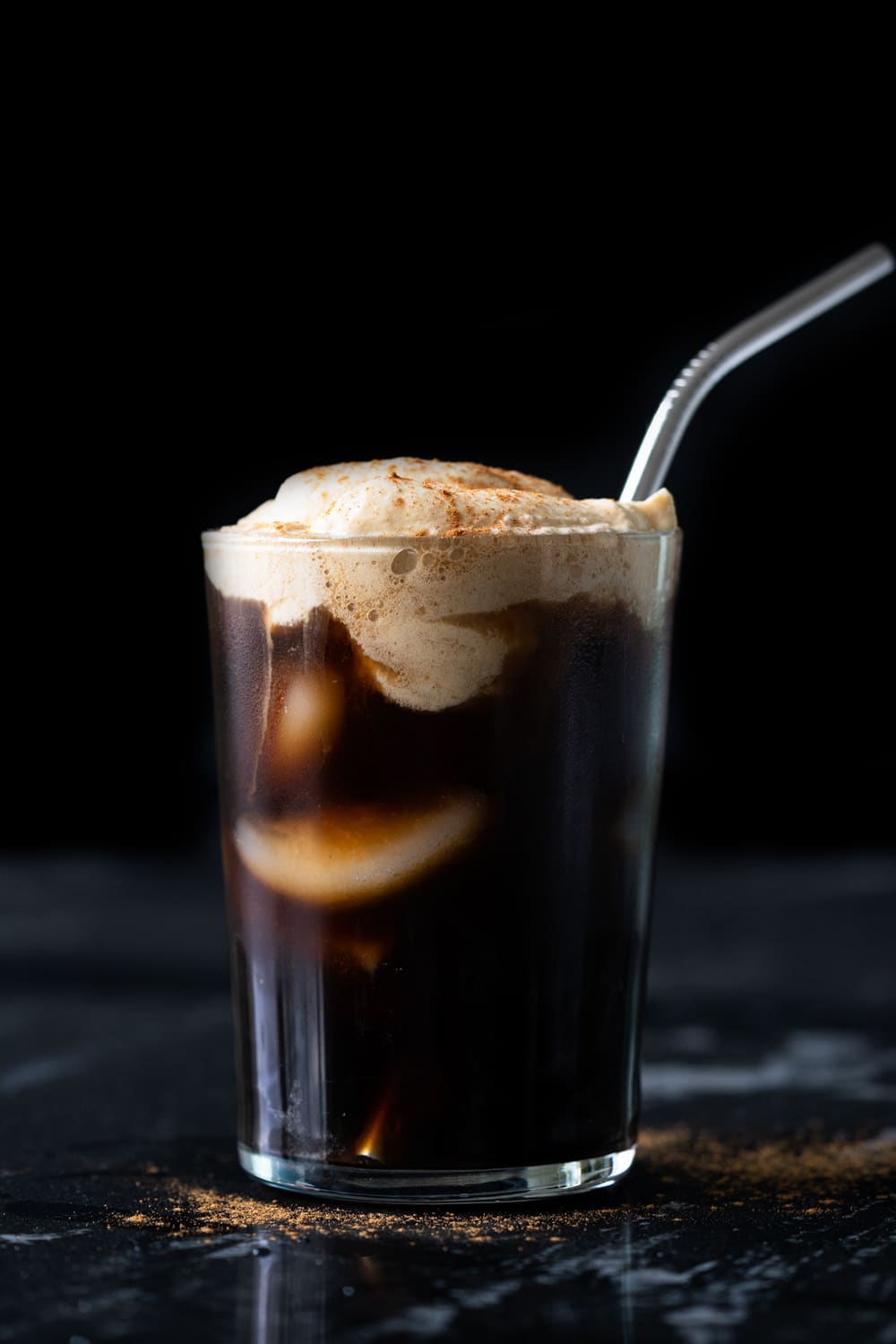 A keto pumpkin cream cold brew in a tall glass with a metal straw