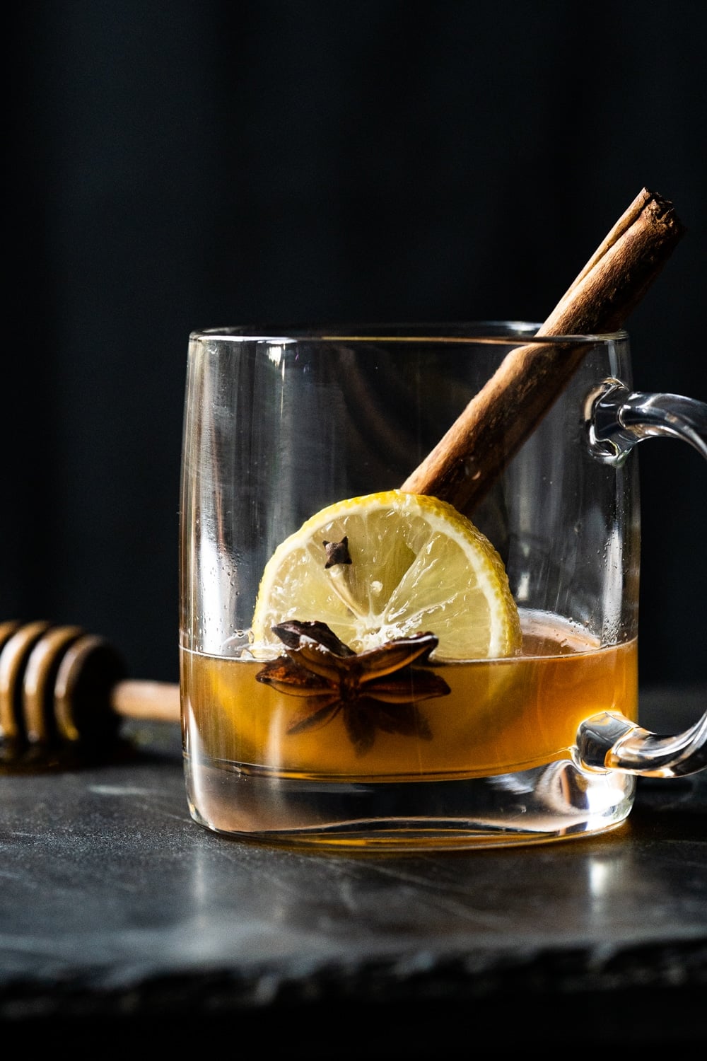 Preparing a keto hot toddy with cinnamon, lemon, star anise, cloves