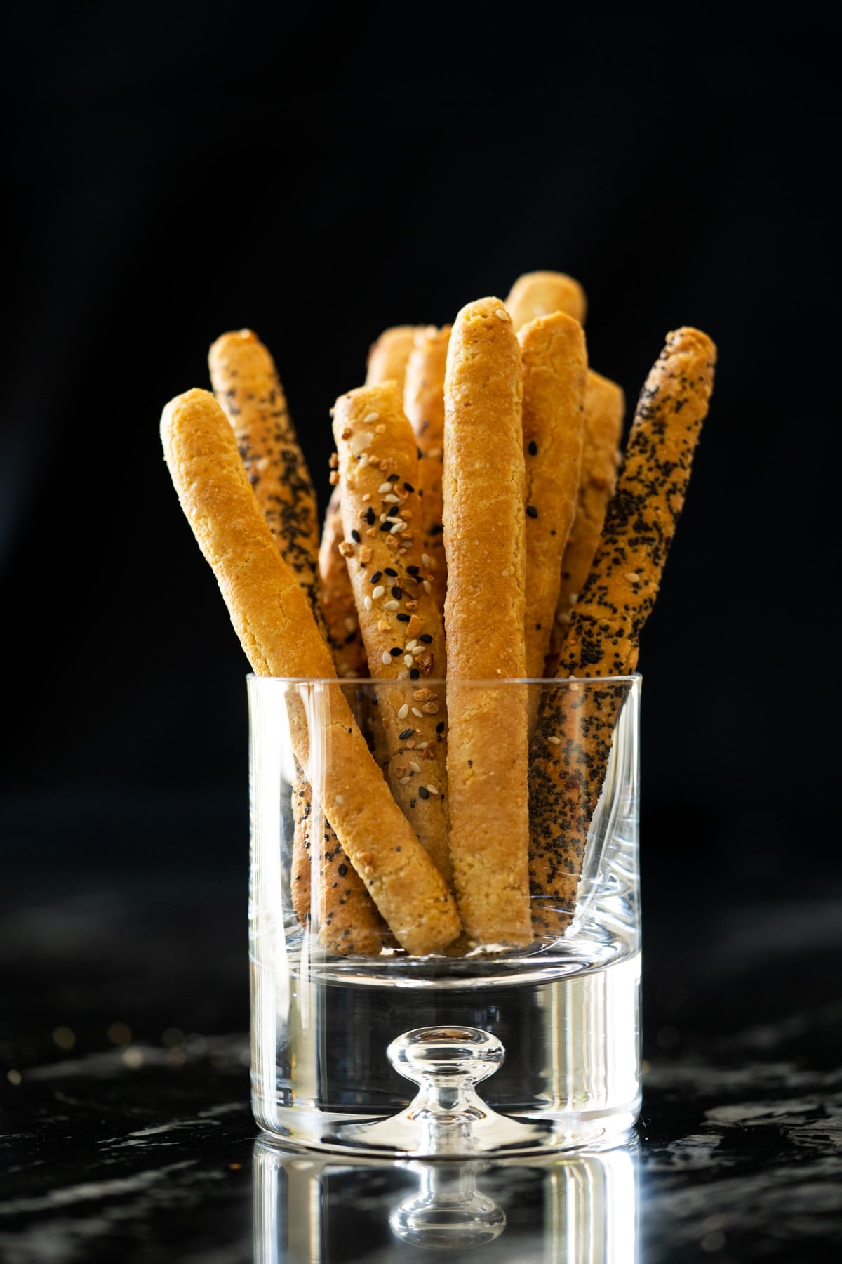 Keto breadsticks in a glass with a black background