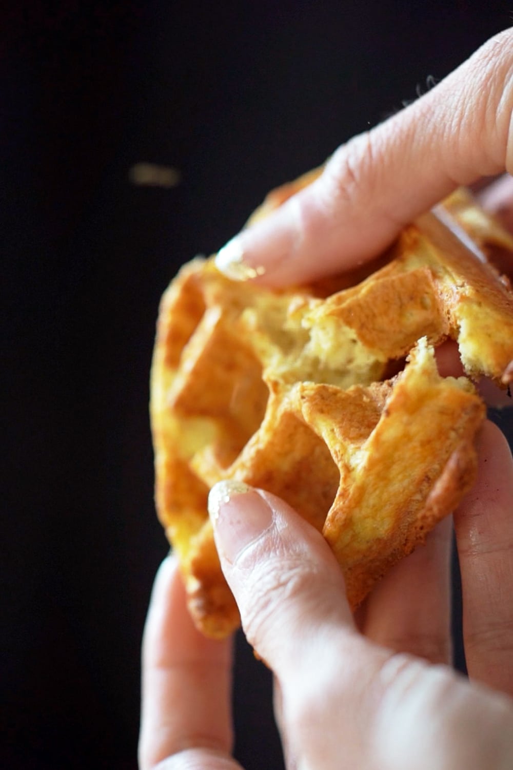 Breaking a keto sourdough waffle in half to show its crisp texture