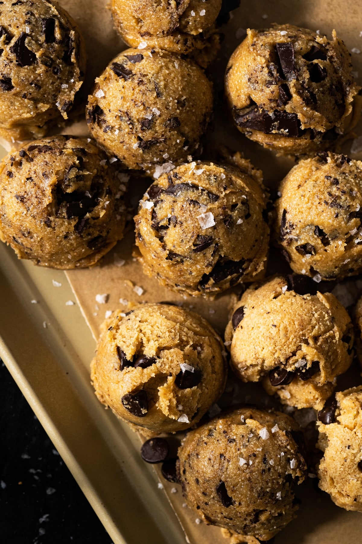 Keto cookie dough with chocolate chips scooped out onto a baking sheet