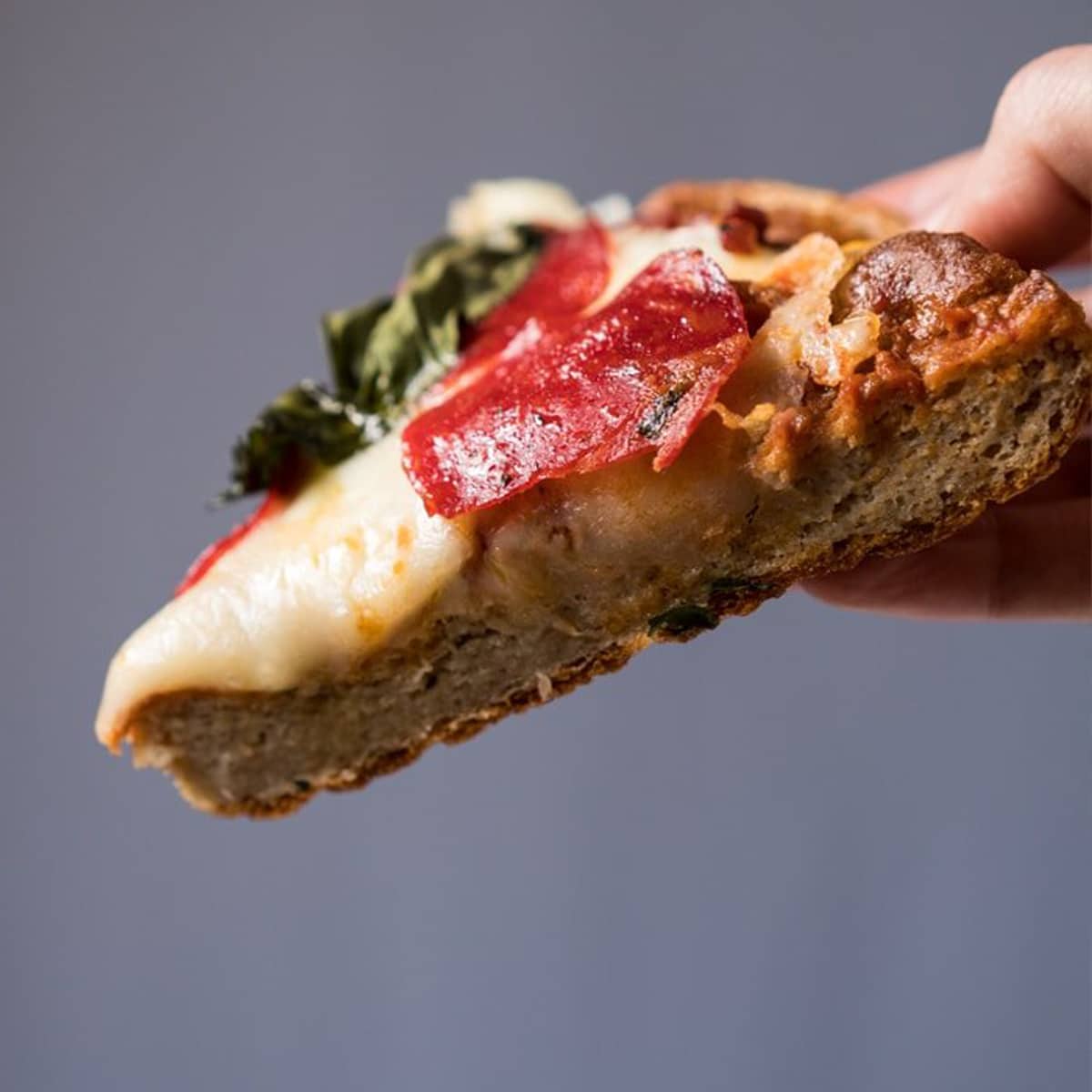 Slice of keto pizza with yeast showing the fluffy texture