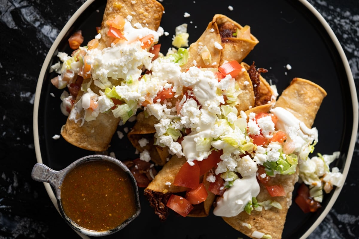 Mexican chicken taquitos topped off with lettuce, cream, cheese and salsa