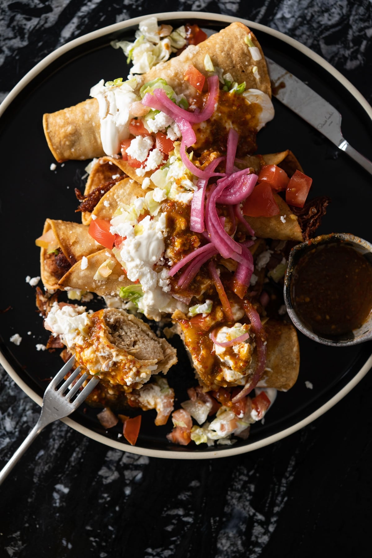 Cutting into a flauta to show the crispy corn tortilla and the shredded chicken filling