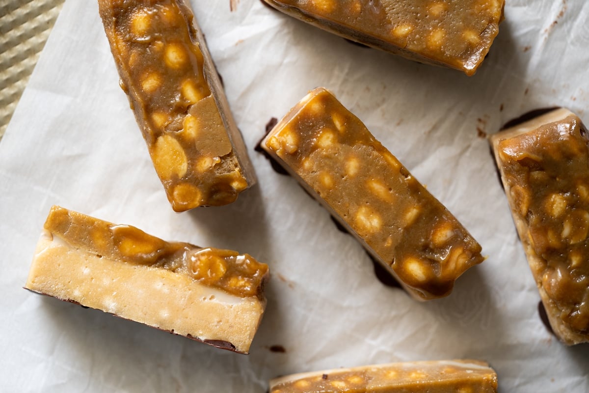 Keto snickers bars on parchment paper ready for the chocolate drizzle