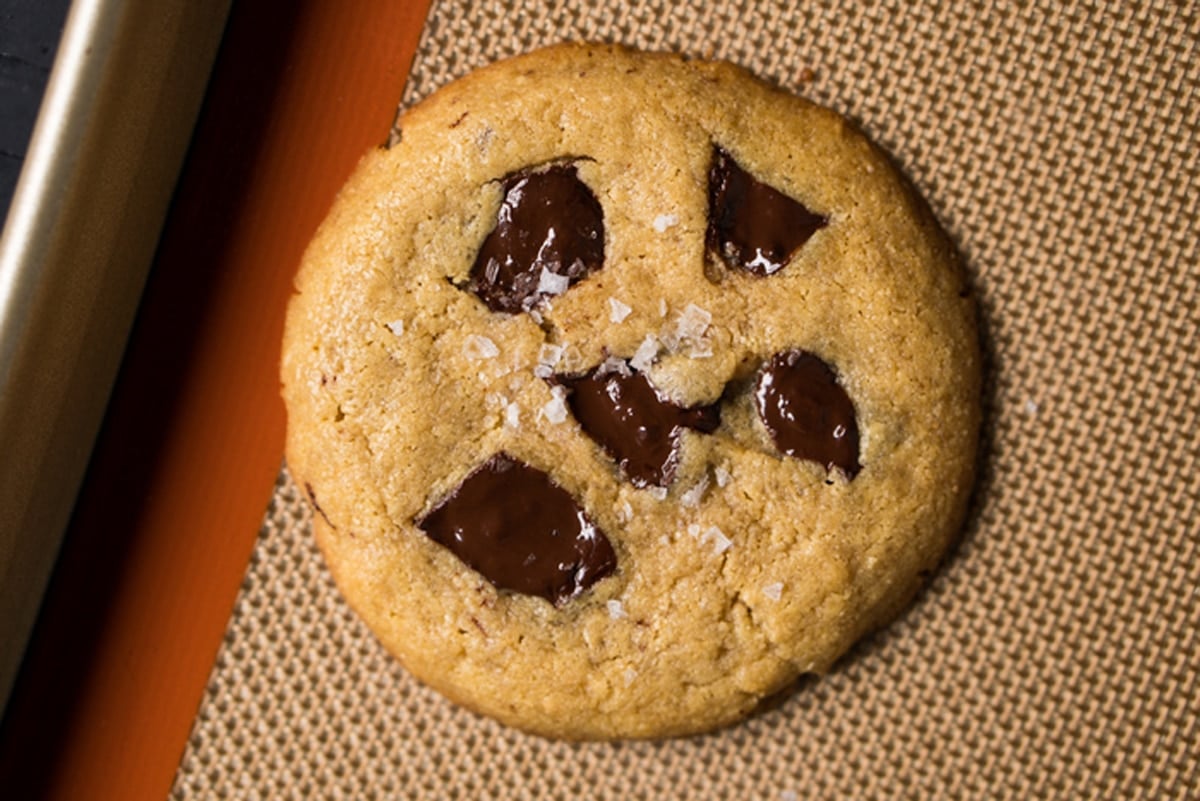Freshly baked flourless cookie with chocolate chunks on a baking tray