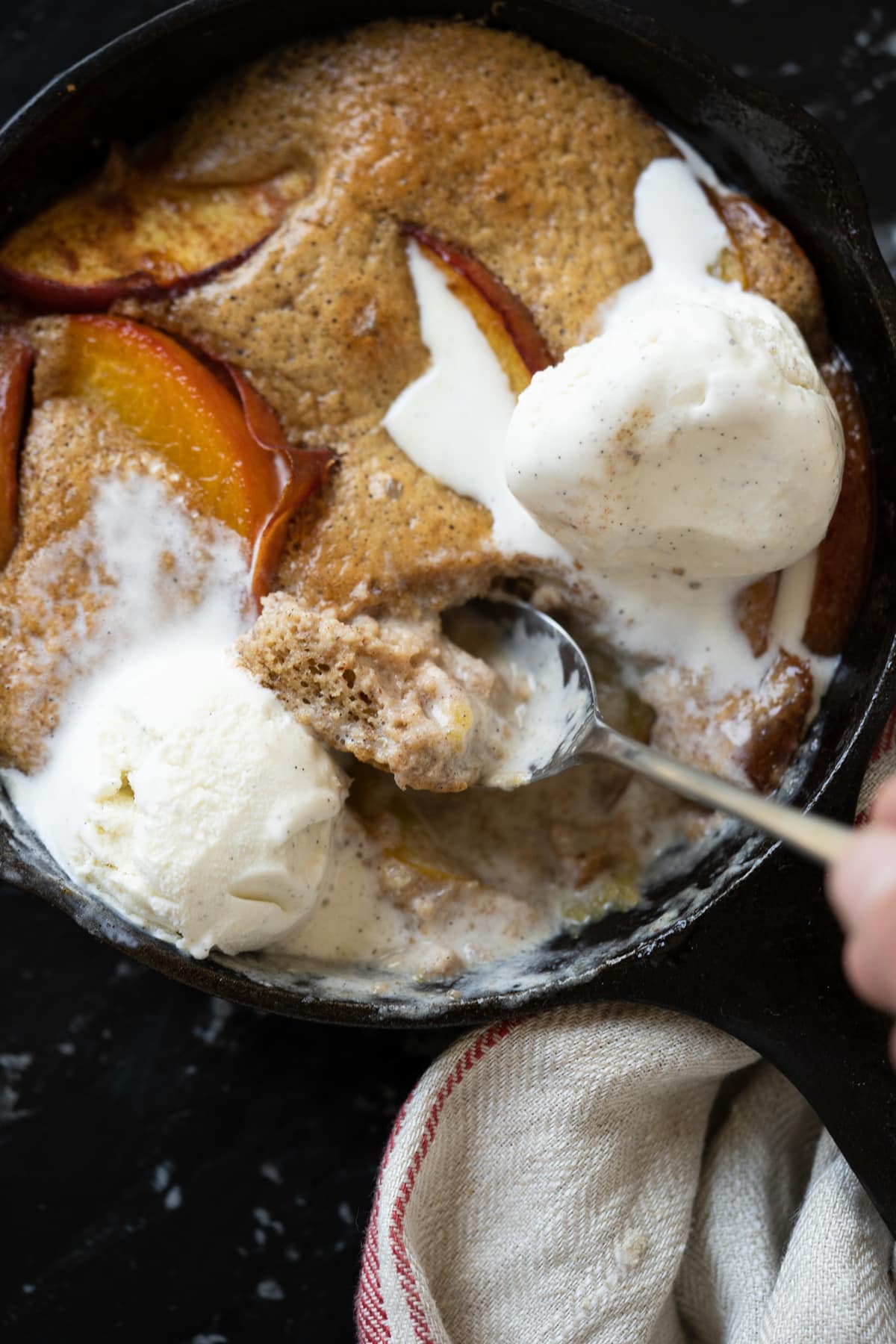 Taking a spoonful of keto peach cobbler showing the fluffy cake like texture