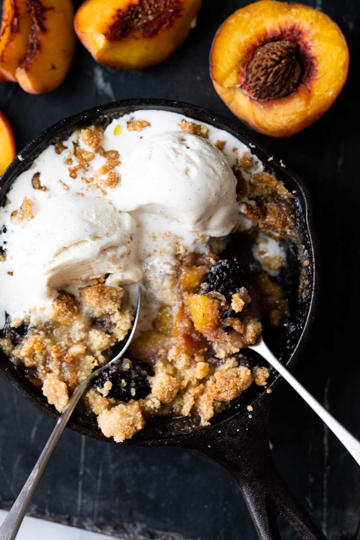 Keto peach and blackberry crisp baked in a skillet and served with two scoops of vanilla ice cream