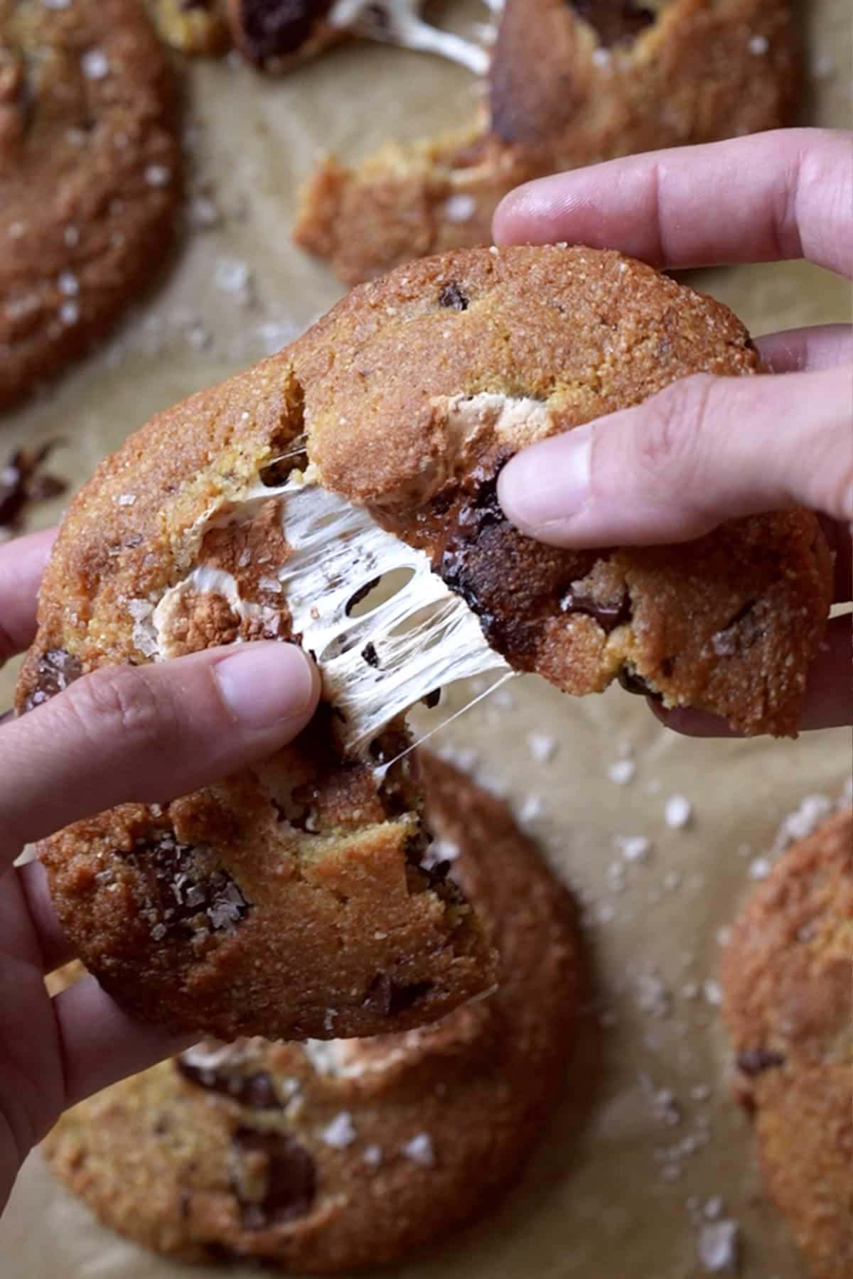 Splitting a s'more cookie in half to show the melted marshmallow texture in the center