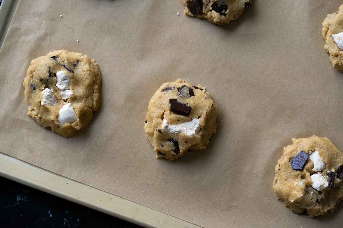 Unbaked cookie dough with marshmallows and chocolate chunks on a baking sheet