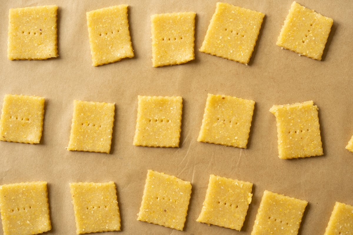 Unbaked keto cornbread crackers on a baking tray with parchment paper