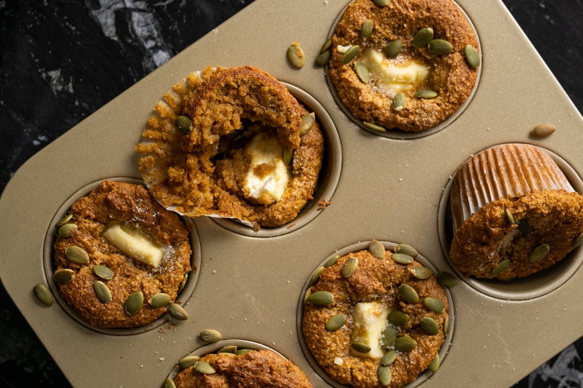 Closeup of keto pumpkin muffins filled with cheesecake and garnished with pumpkin seeds