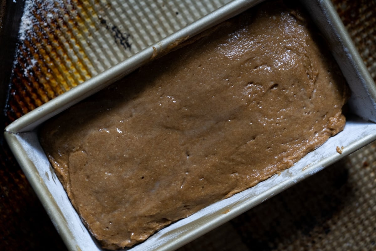 Transferring the almond flour gingerbread batter to a loaf pan and smoothing it out with a wet spatula