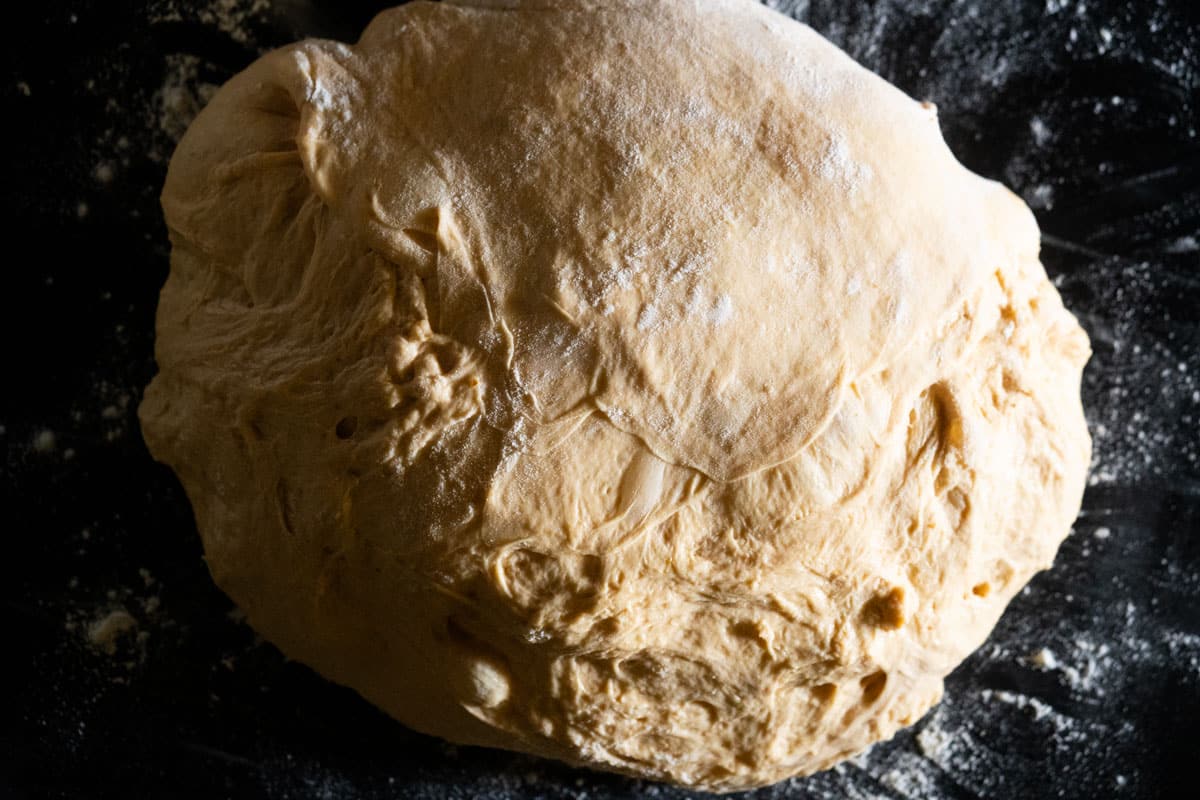 Pumpkin sourdough dough on a black marble pastry slab, after the first proof waiting to be shaped