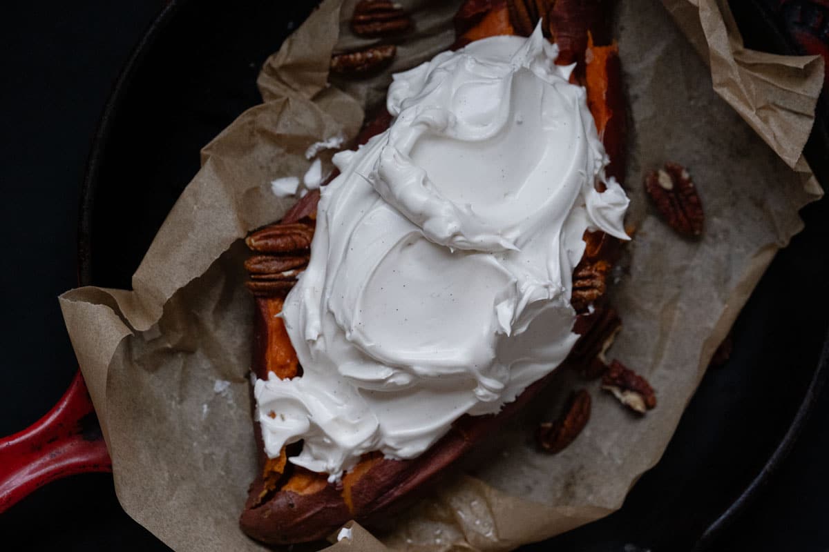 Closeup of honey marshmallow fluff atop a baked sweet potato showing its fluffy and glossy texture