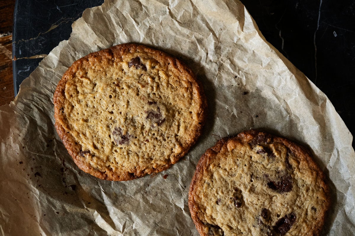 Showing the pale color and bubbly texture in a sourdough chocolate chip cookie resulting from over fermentation