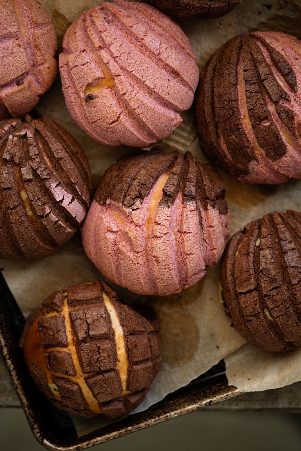Closeup Mexican sourdough conchas with strawberry and chocolate seashell coatings